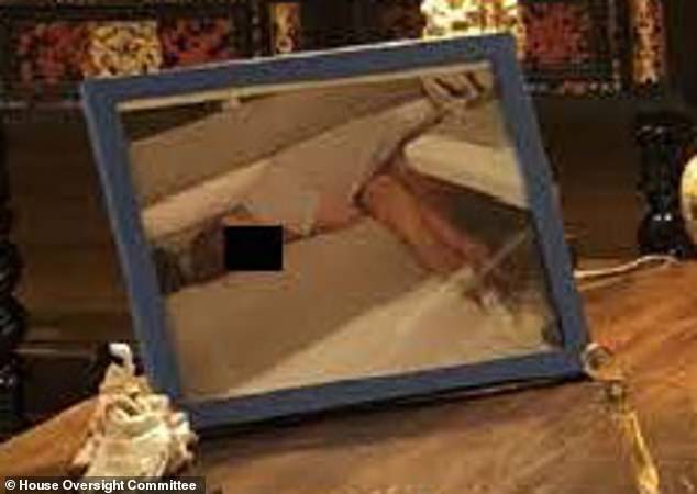 A framed photo on the right corner of the desk facing toward Epstein, appears to show a person lying down. A black box has been placed over their face to protect their identity