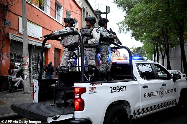 Mexican National Guard special forces escort an ambulance from the forensic service upon its arrival at the Specialized Prosecutor's Office for Organized Crime (FEMDO) headquarters in Mexico City on February 22, 2026. Mexico confirmed on February 22, 2026, that soldiers killed a powerful drug cartel leader who was one of the most wanted men here and in the United States. Nemesio Oseguera, the 59-year-old leader of the violent Jalisco New Generation Cartel, was wounded in a clash with soldiers in the town of Tapalpa and died while being flown to Mexico City, the army said in a statement. (Photo by Alfredo ESTRELLA / AFP via Getty Images)