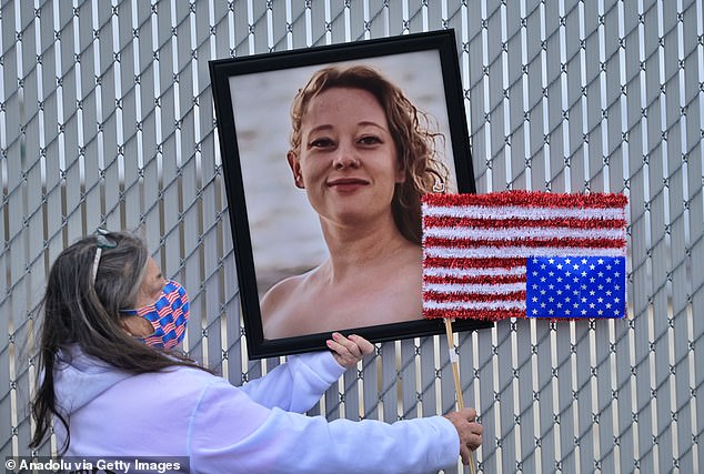 A framed picture of Good, who was killed by an ICE agent in January, is hung outside of an immigration detention facility