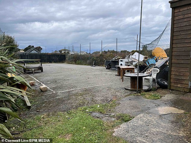 A tennis court at the site featuring a pile of old furniture, car tyres and a washing machine