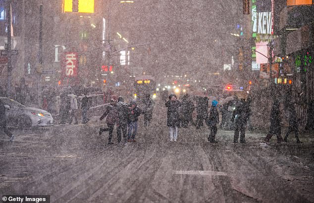 NEW YORK, NEW YORK - FEBRUARY 22: People admire the snow in Times Square on February 22, 2026 in New York City. A major winter storm is expected to hit the Northeast and Mid-Atlantic regions, bringing blizzard conditions with the potential for up to 23 inches of snow in New York City. A blizzard warning has been issued for large areas of the East Coast.  (Photo by Ryan Murphy/Getty Images)