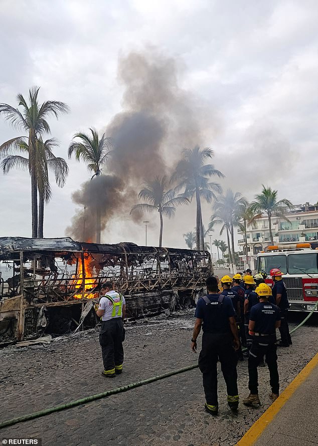 Firefighters work to extinguish flames from buses set on fire by members of organized crime in Puerto Vallarta, Mexico, on Sunday