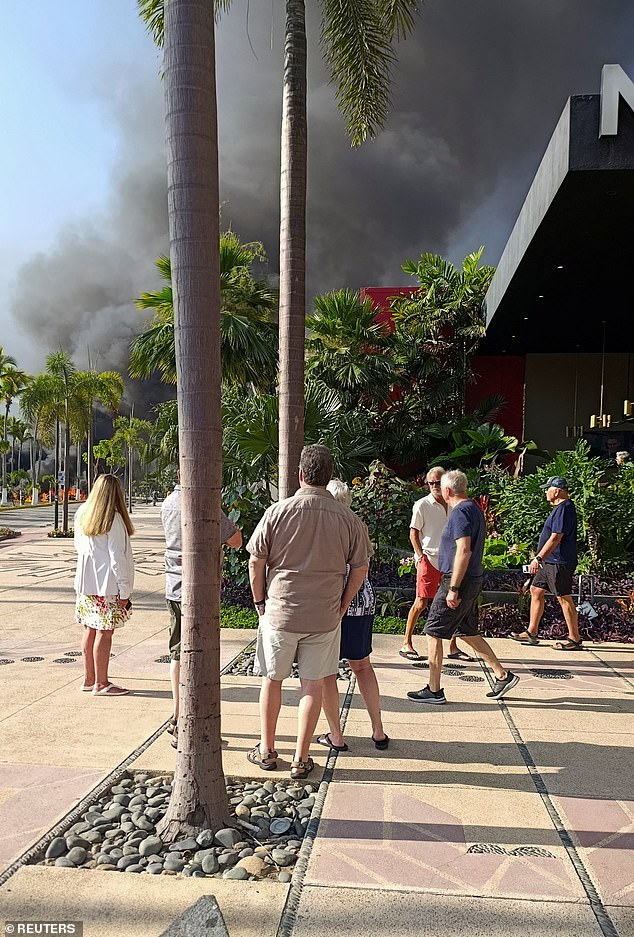 Tourists watch a column of smoke after members of organized crime carried out roadblocks and burned down some businesses in Puerto Vallarta, Mexico on Sunday