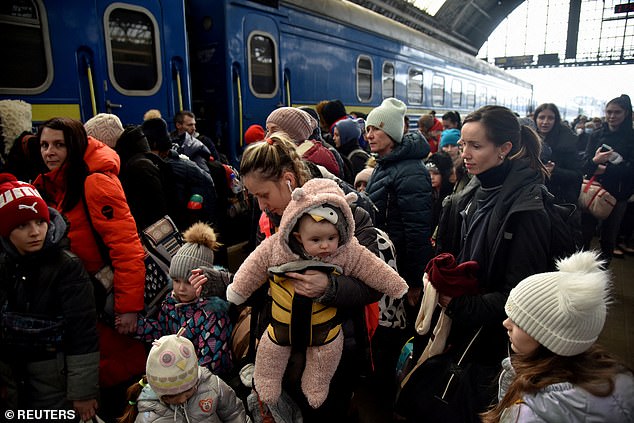 Refugees gather to board a train to Poland in Lviv in March 2022. While making their escape from Ukraine Mrs Rizak said: 'When we left Ukraine I had no emotion. I was just trying to survive'