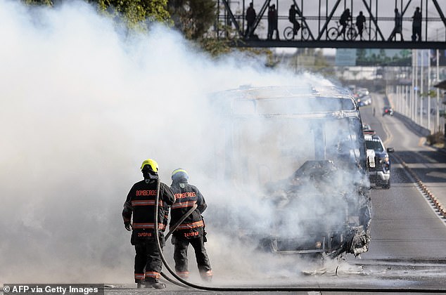 Firefighters extinguish a burning bus set on fire by cartel members