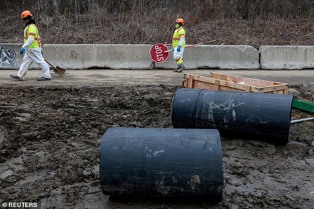 Workers walk along the Clara Barton Parkway during the repair of the Potomac Interceptor