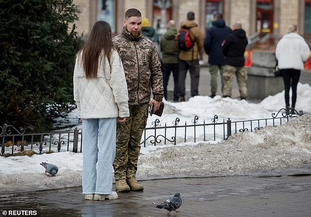 People stand during a minute of silence in Kyiv to mark the fourth anniversary of the full-scale Russian invasion