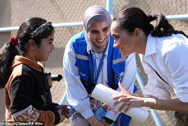 The Duchess of Sussex meets a young girl during the couple's tour of Jordan today