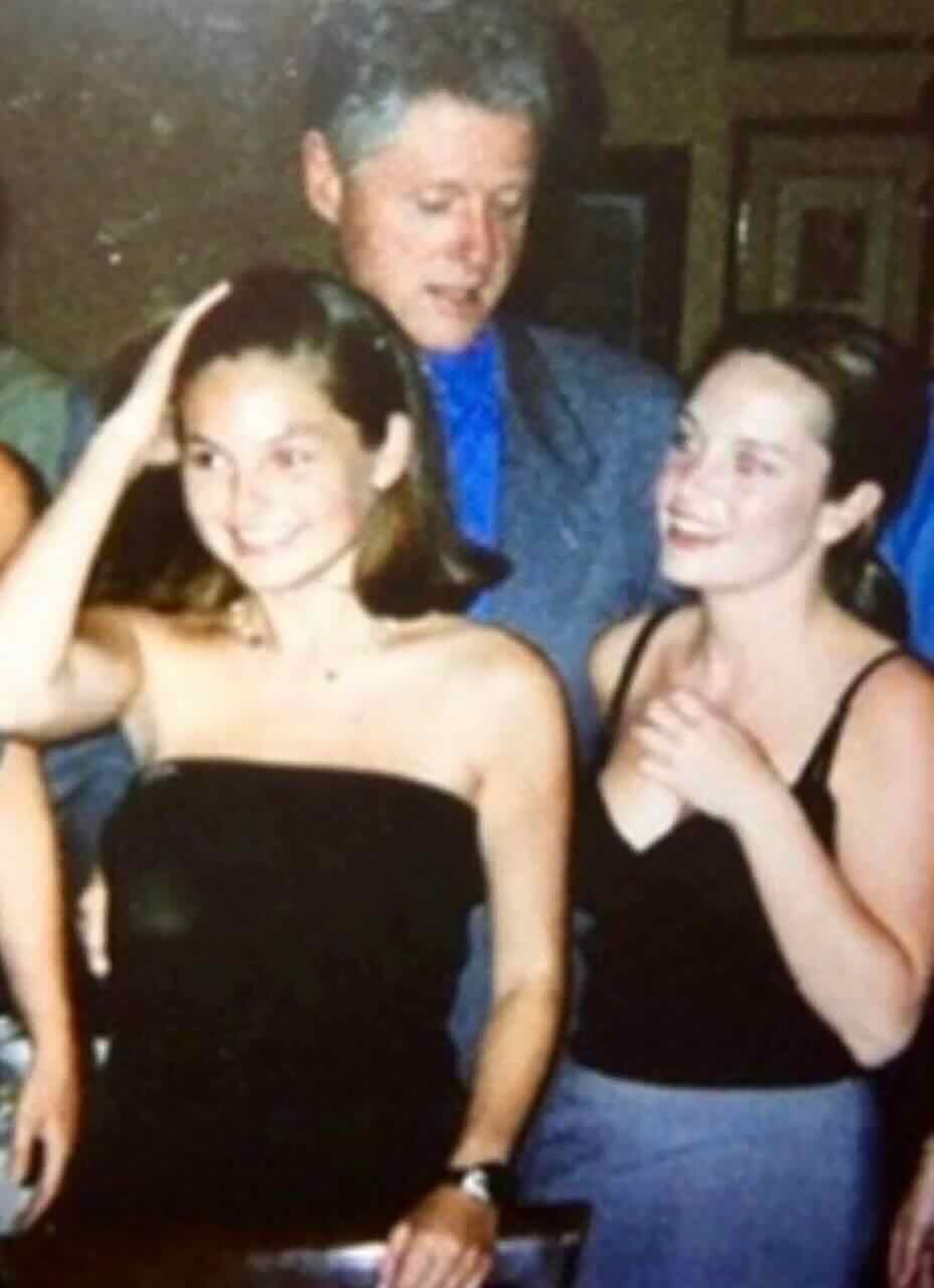 Bill Clinton standing behind two smiling women.