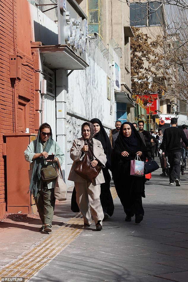 People run for cover following explosions in Tehran on Saturday