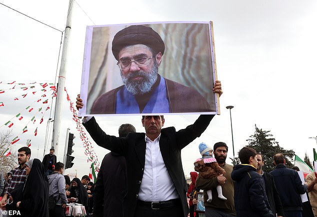 An Iranian man holds a picture of Mojtaba Khamenei, the son of the Iranian Supreme Leader