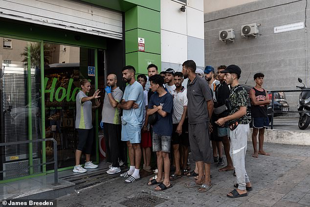 Migrants queue outside a supermarket in Ceuta after entering the Spanish enclave from neighbouring Morocco