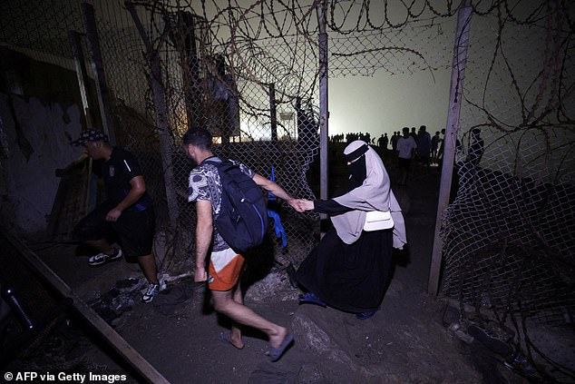 Migrants pass through a broken fence as they leave Spain's North African enclave of Ceuta towards the Moroccan town of Fnideq, on the Morocco-Spain border