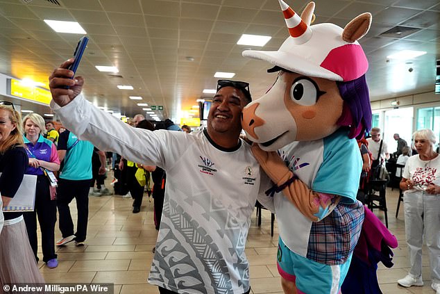 A Cook Islands athlete takes a photo with mascot Finnie