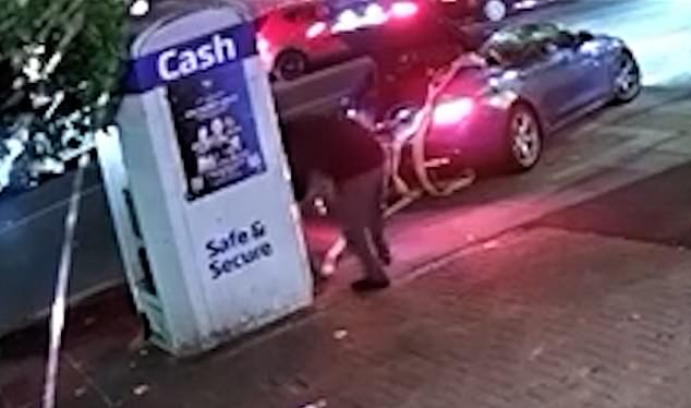 Moments earlier the hammer-wielding crook and the driver attach cables to the ATM