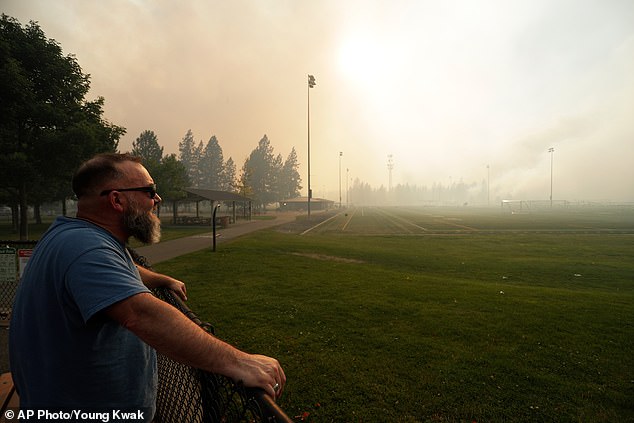 Andrew Rowley watches Old Trails Fire from Dwight Merkel Sports Complex after evacuating, Saturday, August 1, 2026, in Spokane, Washington