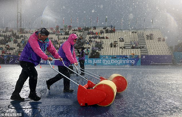 Groundstaff try to clear track at Scotstoun during a downpour