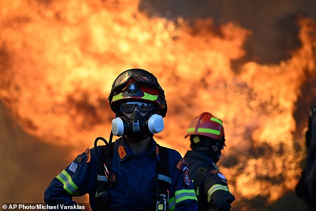 A firefighter stands as flames rise during a wildfire in Greece