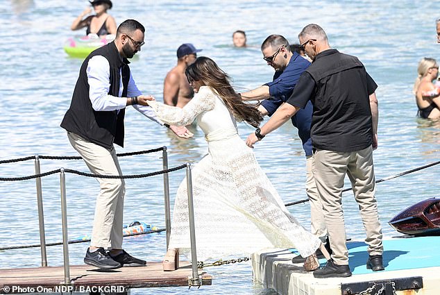 Achilles' heels! US ambassador to Greece Kimberly Guilfoyle almost totters into the sea as she arrives at 'gay mecca' in SIX INCH platforms