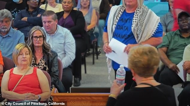 A person is seen wearing an anti-data-center shirt at the city council meeting