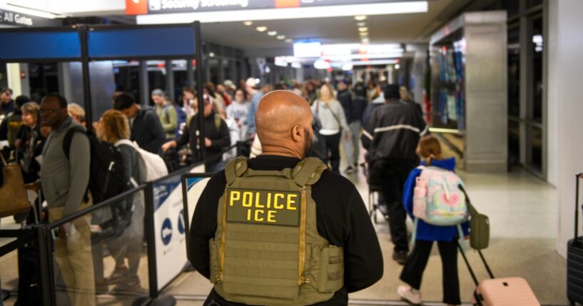 An ICE agent stands alongside a long line of travelers waiting to pass through a TSA Checkpoint at the Philadelphia International Airport on March 28, 2026, in Philadelphia, Pennsylvania.