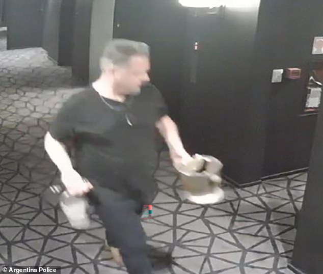 A hotel worker delivers scotch and champagne to Liam's room