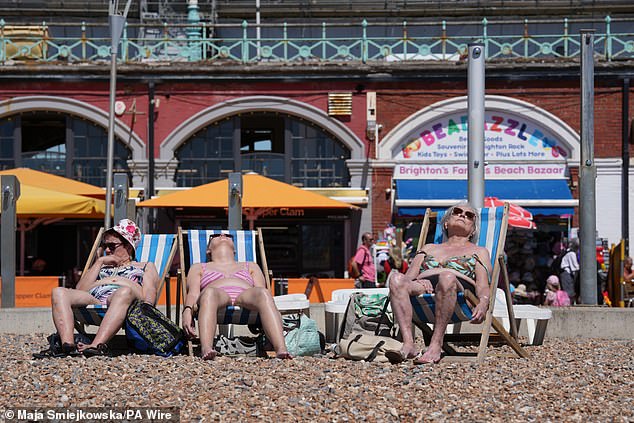 Three women lie in the sun on the beach in Brighton, East Sussex, on Friday