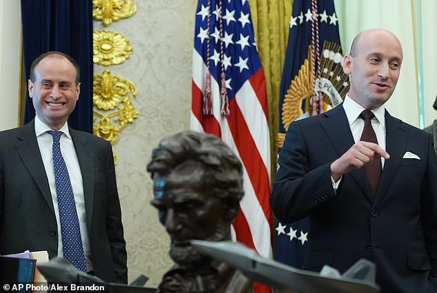 Scharf grins as as White House deputy chief of staff for policy Stephen Miller speaks in the White House