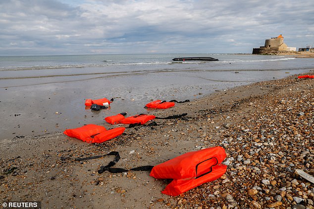 Life jackets and a damaged dinghy are seen on the beach after migrants jumped to get back onto the shore