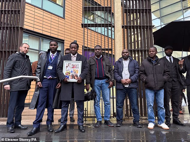 Alfil Bash, (holding photo frame), father of Fares, Joury and Mohammed, attending the appearance of Ali at Bristol Magistrates' Court last December