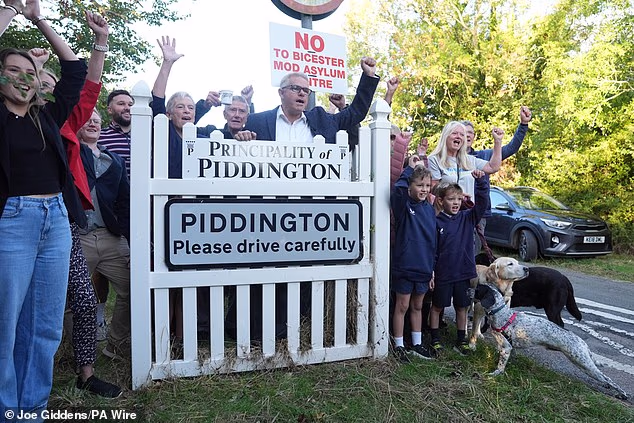 Local residents pose with a 'Principality of Piddington' sign in the Oxfordshire village following the referendum result