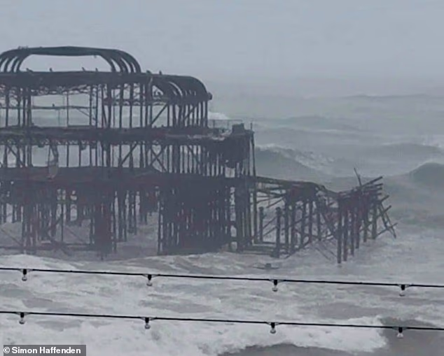 One side of Brighton's historic West Pier falls into the water today as it is hit by large waves