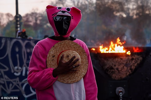 A protester wearing a costume stands next to a burning fire during a demonstration organised by labour unions as part of nationwide protests