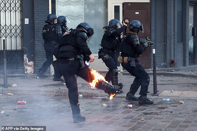 A protester wearing a costume stands next to a burning fire during a demonstration organised by labour unions as part of nationwide protests  in Paris
