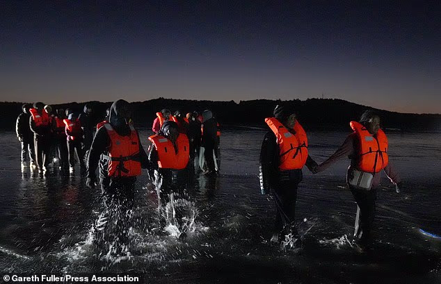People thought to be migrants wade in the water as they attempt to board a small boat off the coast of Hardelot, France